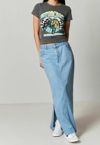 Grå grafisk t-shirt med motocross-design, parret med en højtsiddende, lyseblå denim maxi-nederdel med frontlukning med knapper og sideslids.