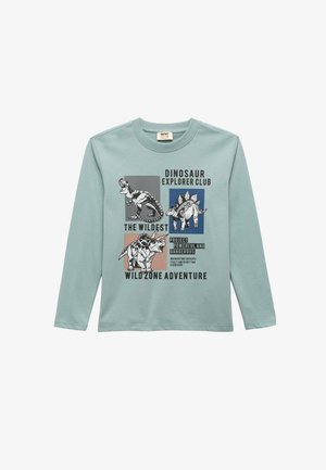 Helles blaues Langarmshirt mit Dinosauriergrafiken und Text. Die Materialien scheinen weich zu sein; das Design umfasst bunte Quadrate und fette Schriftzüge.