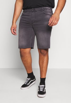 Szare szorty z denimu z postrzępionym brzegiem, pięcioma kieszeniami i zapięciem na guzik. Noszone z czarnymi skarpetami oraz czarno-białymi tenisówkami.