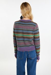 Lila Strickpullover mit mehrfarbigen horizontalen Streifen und gemusterten Akzenten. Gerippte Bündchen und Saum, kombiniert mit blauen Jeans.