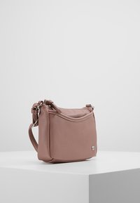 Kožená kabelka v jemném taupe s kulatým tvarem, vybavená plochým vrškem, nastavitelným popruhem a stříbrným kováním. Hladká textura.