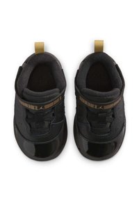 Zapatos negros con un acabado de charol brillante y una correa negra texturizada. Presentan punta redonda, interior acolchado y detalles dorados en la correa.