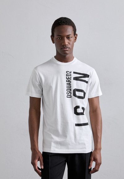 T-shirt en coton blanc avec un grand texte graphique noir vertical "DSQUARED2 ICON" sur le devant. Manches courtes et col rond.