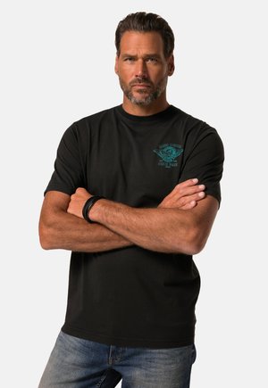 Sort bomuld t-shirt med turkis grafisk design på venstre bryst, rund halsudskæring og korte ærmer. Bæres med blå jeans.