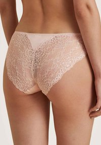 Lace onderbroekjes in zachtroze met ingewikkelde bloemmotieven, voorzien van een naadloos achterontwerp en delicate golvende randen.