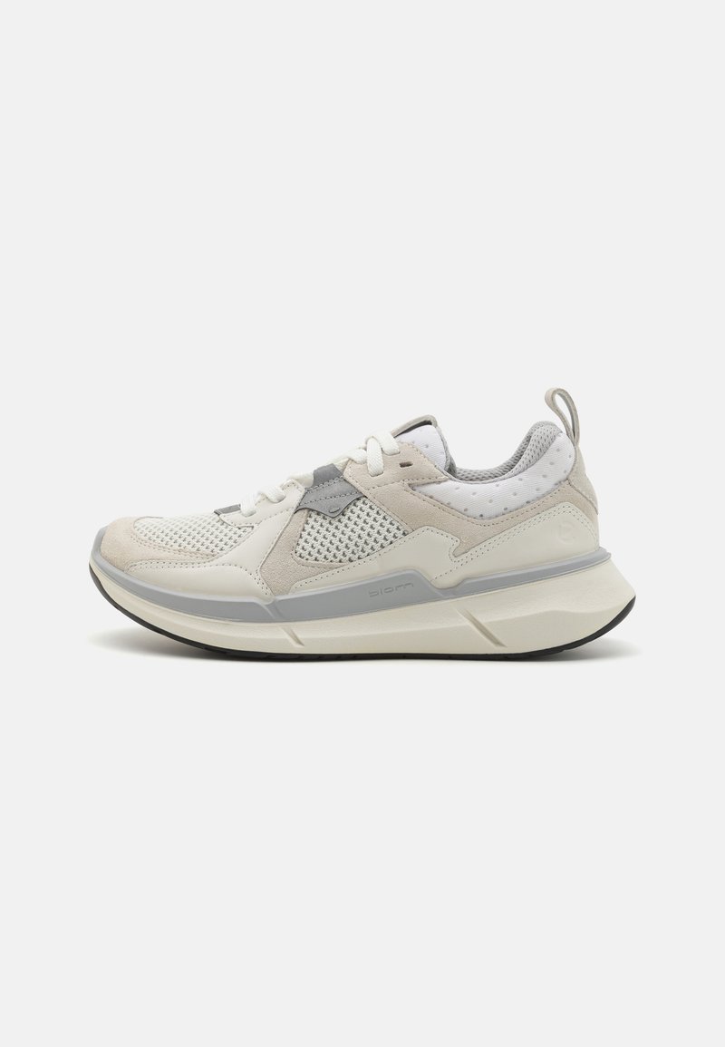 Baskets de sport gris clair en matériaux mesh et daim, avec une semelle intermédiaire blanche épaisse et de minimalistes accents gris. Présente un tirant à l'arrière.