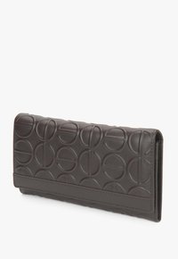 Ciemnobrązowy skórzany portfel z wytłoczonym okrągłym wzorem, prostokątny kształt i gładka tekstura. Posiada przeszyty brzeg i złożoną konstrukcję.
