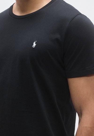 Črna bombažna majica s krožnim izrezom, z majhnim belim logotipom polo na levi prsni strani. Gladek tekstura in oprijet dizajn.