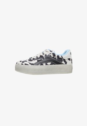 Schwarz-weiße Sneaker mit Kuhmuster, hellblauem Kragen und grauer Plateau-Sohle; seitlich mit einem schwarzen Logo versehen.