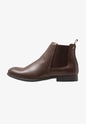 Botte Chelsea en cuir marron avec panneau élastique sur le côté, talon bas, tirette à l'arrière et bout arrondi, vue de l'extérieur.