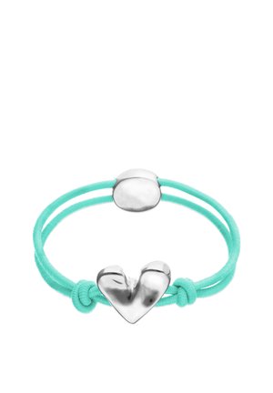 Pulsera de cordón doble turquesa con charm de corazón plateado pulido y cierre ovalado, asegurada con dos nudos cerca del charm de corazón.