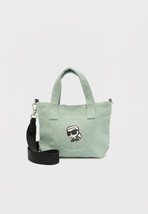 Petit sac fourre-tout vert clair avec doubles poignées, bandoulière noire amovible, et logo cartoon représentant une personne portant des lunettes de soleil.