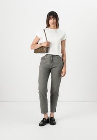Bílý tričko s krátkým rukávem, šedé džíny s vysokým pasem, černé loafers a zelená kabelka přes rameno. Minimalistický design s rovnými nohavicemi.