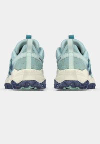 Paire de chaussures de sport bleu clair et blanc avec des semelles à motifs bleu foncé, vues de dos sur un fond uni.