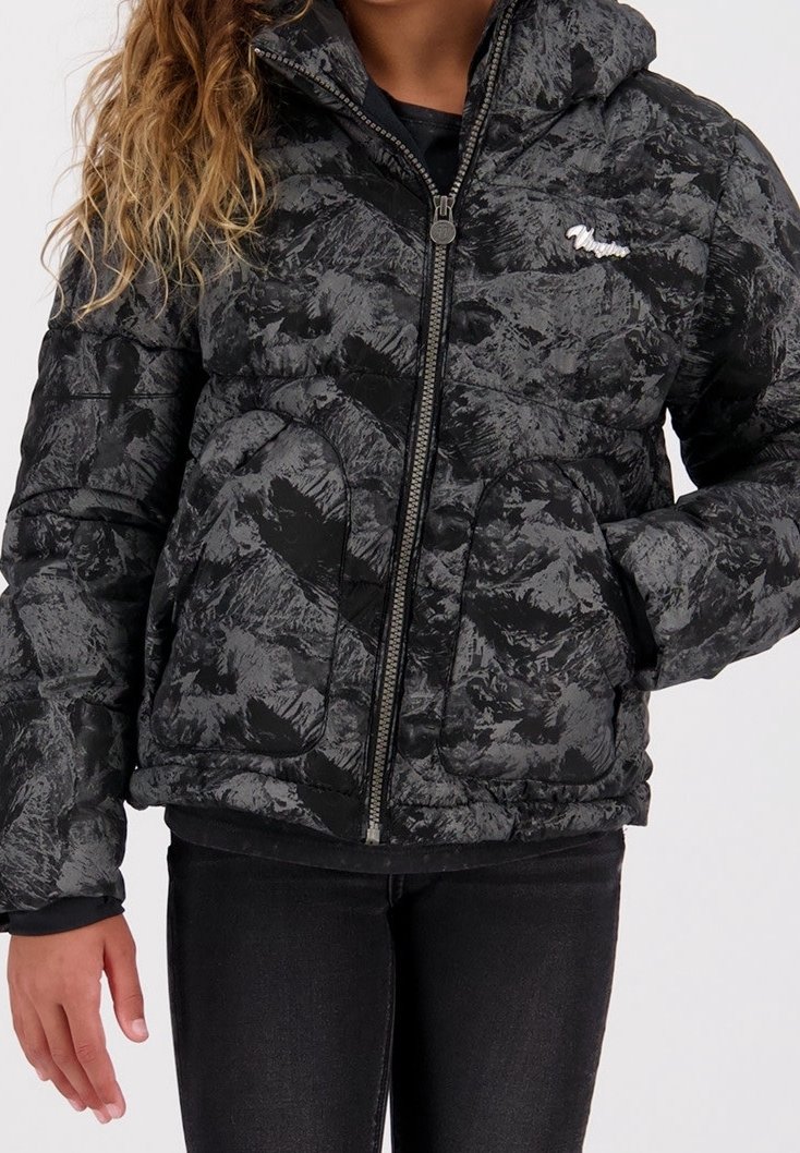 Doudoune noire et grise à motifs avec fermeture éclair à l'avant et poches, portée par une personne aux cheveux ondulés et pantalon noir.