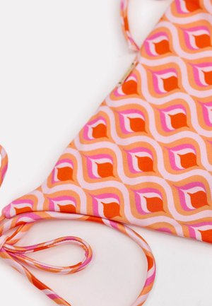 Gros plan sur un haut de bikini à motifs géométriques rose, orange et rouge, avec une fine bretelle ajustable, sur fond blanc.