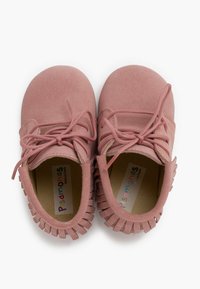 Zapatos infantiles de ante rosa con punta redonda, cierre con cordones y detalles de flecos a los lados. Material suave y texturizado con un diseño ligero.