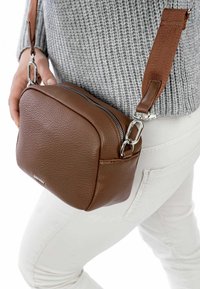 Borsa a tracolla in pelle marrone con forma quadrata, superficie texturizzata, accessori in argento e tracolla in tessuto. Chiusura con zip sulla parte superiore.