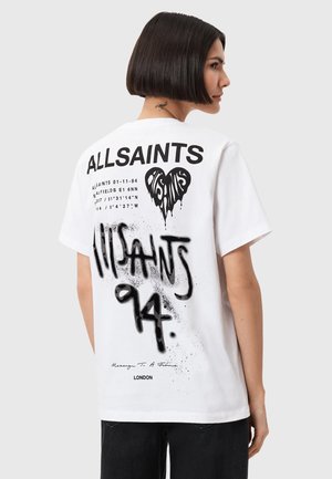 T-shirt in cotone bianco con audaci grafiche nere, inclusi il testo "ALLSAINTS" e un design a forma di cuore. Il retro presenta dettagli con effetto spray.