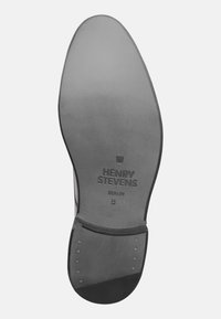 Sohle eines Anzugschuhs mit dem eingeprägten "HENRY STEVENS BERLIN 8", mit glatter Oberfläche und verstärktem Absatz mit Metallnieten.
