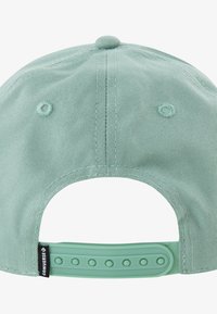 Mētru zaļa cepure ar teksturētu audumu, regulējamu snapback aizdari un divām ventilācijas atverēm. Uz siksnas ir logo etiķete.