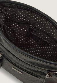 Schwarze Handtasche mit Textur, ausgestattet mit einem gemusterten Innenfutter in weißen Punkten, Reißverschlusstaschen und metallischen Akzenten.