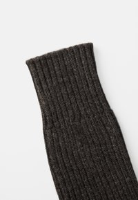 Rippensocken in Dunkelgrau aus einem weich strukturierten Material mit umgeschlagenem Bund. Das Material wirkt warm und ist ideal für kaltes Wetter.