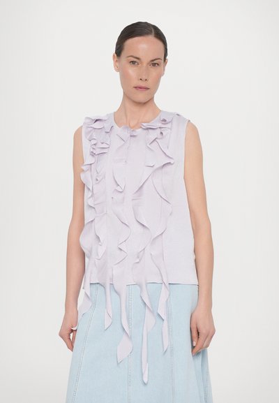 Lilac sleeveless top featuring multiple ruffled layers, soft texture, and a round neckline, paired with a denim skirt.