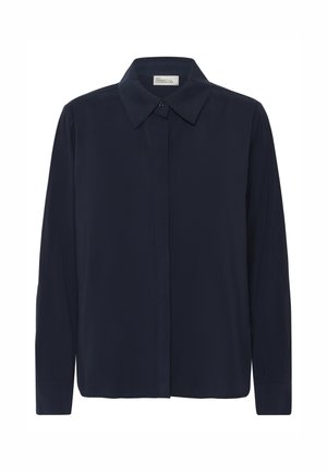 Tumši zils krekli ar garām piedurknēm, klasiska apkakle, priekšpusē ar pogu aizdari un gludu auduma struktūru. Raksturo taisns apakšmalas griezums un pieguļošs siluets.