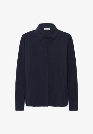 Tumši zils krekli ar garām piedurknēm, klasiska apkakle, priekšpusē ar pogu aizdari un gludu auduma struktūru. Raksturo taisns apakšmalas griezums un pieguļošs siluets.