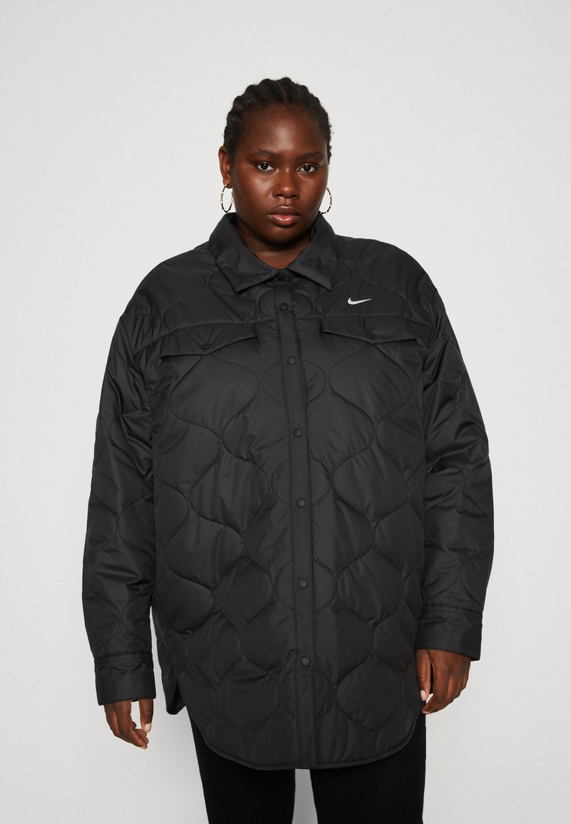 Veste noire matelassée avec un devant à boutons, un col haut et un logo Nike subtil. Fabriquée à partir d'un matériau lisse et isolant avec une coupe décontractée.