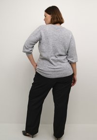 Gray knitted sweater with three-quarter sleeves and ribbed hem, paired with black wide-leg trousers and pointed black shoes.