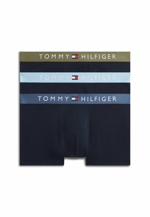 Ung mand stående barfodet iført mørkeblå Tommy Hilfiger boxershorts med logo på linningen på hvid baggrund