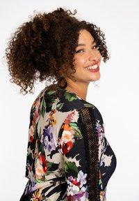 Bloemmotief top met een zwarte achtergrond en bloemen in verschillende kleuren, kantaccenten op de mouwen en een ronde halslijn.