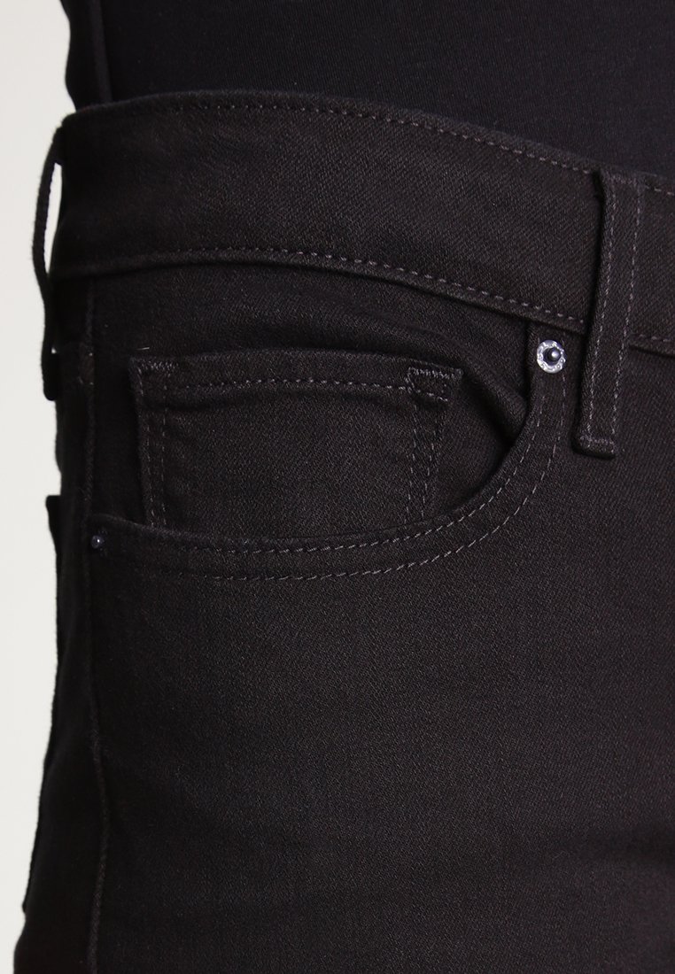 Jeans de mezclilla negra con un diseño ajustado, que presentan un bolsillo frontal, costuras visibles y un detalle de botón metálico en la cintura.