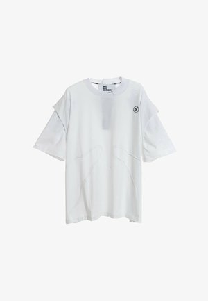 Camiseta blanca de manga corta con escote redondo, que presenta costuras curvas únicas y un pequeño logo en el lado izquierdo. Material de algodón suave.