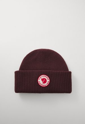 Donkerrode geribbelde gebreide beanie met omgeslagen rand, featuring een ronde rood-witte patch logo van een vossenhoofd en de tekst "Fjällräven Zweden 1960".