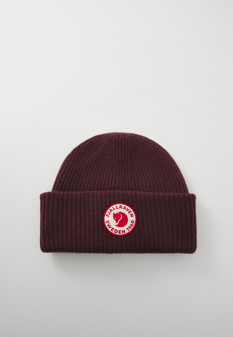 Mørkerød ribbet strikbeanie med foldet skygge, der har et rundt rødt og hvidt patch-logo af et rævehoved og teksten "Fjällräven Sverige 1960".