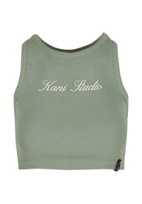 Crop top côtelé en vert atténué avec un col rond, featuring un texte brodé en blanc "Kani Studio" sur le devant et une étiquette de logo discrète.