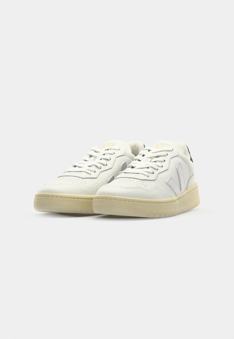 Baskets en cuir blanc avec des accents texturés, bout rond, lacets à l'avant et semelle en caoutchouc beige. Présente un logo discret sur la languette.