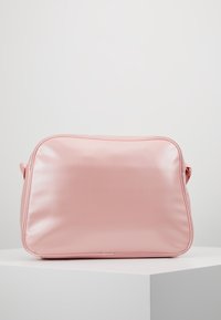 Borsa in ecopelle rosa con una texture liscia, forma arrotondata e cuciture a contrasto. Presenta una chiusura con zip e una tracolla regolabile.