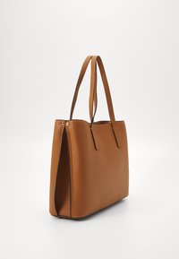Tan leren totebag met een gestructureerd ontwerp, voorzien van twee lange handvatten, een gladde textuur en minimalistische stikseldetails.