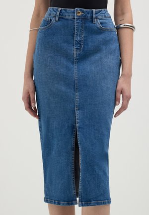 Woman wearing a high-waisted blue denim pencil skirt with a front slit and metal button closure, accessorized with silver bracelets.