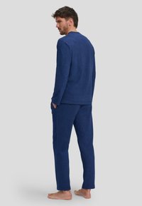 Conjunto de loungewear color azul marino hecho de tela suave, que incluye una camiseta de manga larga y pantalones a juego con un fit relajado y bolsillos laterales.