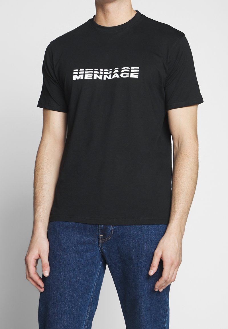 T-shirt en coton noir avec un imprimé textuel blanc disant "MENNACE" avec des épaisseurs variées, encolure ronde, manches courtes et coupe décontractée.