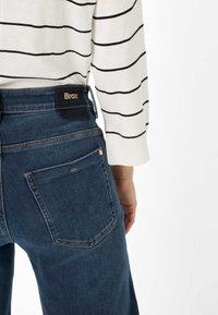 Brax Denim-Jeans in Dunkelblau, mit mittelhohem Bund, geradem Beinverlauf und zwei Gesäßtaschen mit minimaler Nahtdetails.