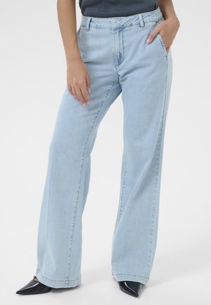 Light blue high-waisted wide-leg jeans made of denim, featuring a front pocket and stitched seams, paired with pointed black shoes.