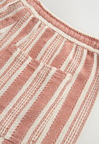 Cotton fabric with alternating red and cream stripes, featuring a textured weave. Includes a small pocket with a stitched edge.