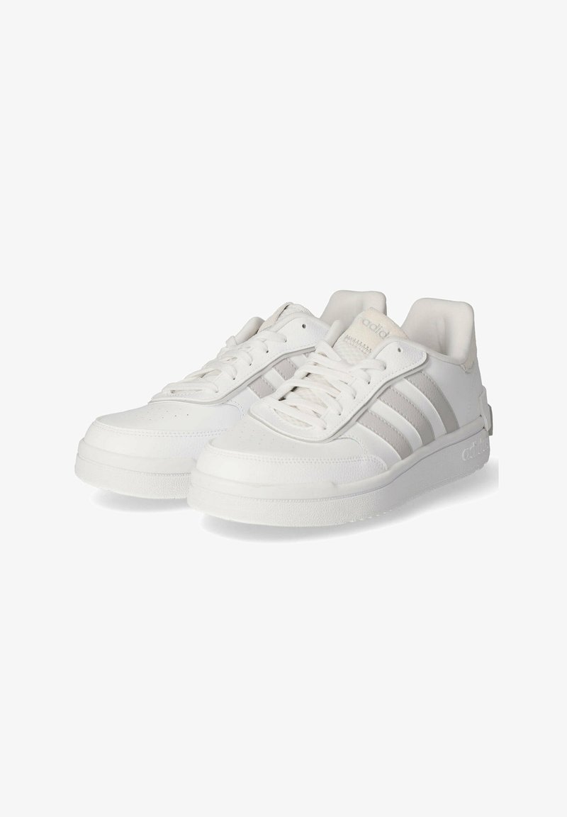 Zapatillas deportivas blancas de diseño bajo, hechas de un material similar al cuero, con tres rayas texturizadas, cordones planos y una suela de goma.