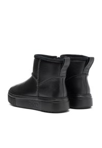 Botas de cuero negro hasta el tobillo con puntera redondeada, suela plana y costuras visibles. Cuentan con un cuello acolchado y una cinta en la parte trasera para ponérselas con facilidad.